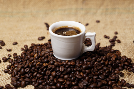 Cup of coffee on sackcloth with coffee beansの写真素材