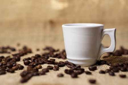 Cup of coffee on sackcloth with coffee beansの写真素材