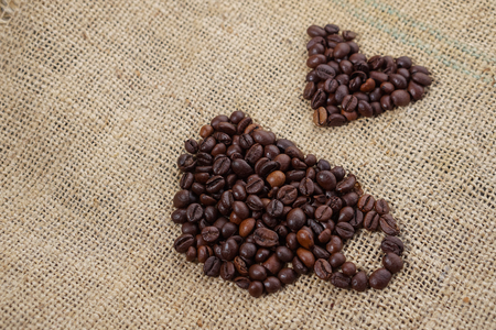 Roasted coffee beans placed in the shape of a cup and placed on sackclotheの写真素材