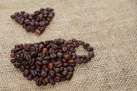 Roasted coffee beans placed in the shape of a cup and placed on sackclotheの写真素材