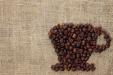 Roasted coffee beans placed in the shape of a cup and placed on sackclotheの写真素材