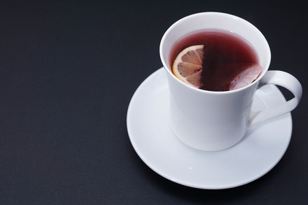 Red tea in white cup with lemon slice  on dark backgroundの写真素材