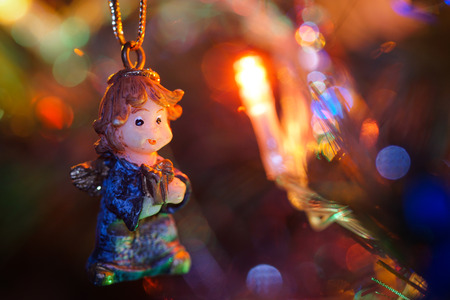 A miniature ornamental figurine on a Christmas tree with lights in backgroundの写真素材