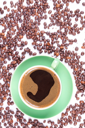 Coffee in green cup surrounded with coffee beansの写真素材