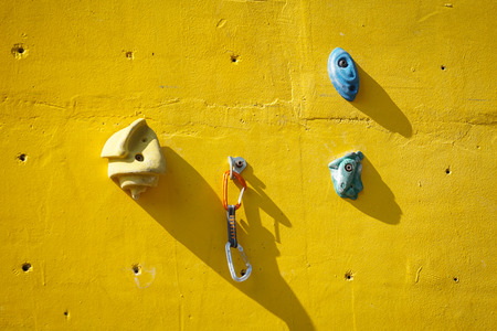 yellow artificial climbing wall with holds outdoor