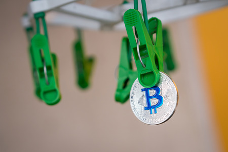 Green clothes peg hold one silver Bitcoinの写真素材