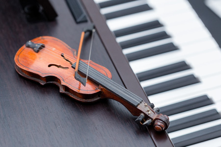 A miniature violine on dark wooden piano