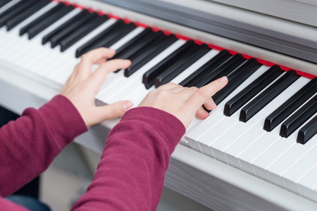Close up of hands of young girl playing white pianoの写真素材
