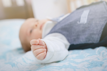 Baby boy sleep in bad. Hand in focus, Blurred background.の写真素材