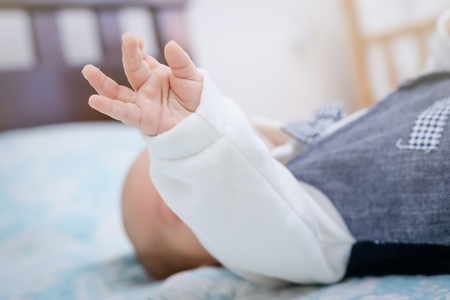 Baby boy lay in bad with hand up in the air.の写真素材