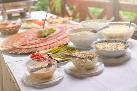 Different types of delicious salads and slices of pork dried meat on large plate. Wedding day food...