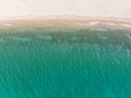 Drone aerial view from above of sandy beach, green and blue sea water.の写真素材