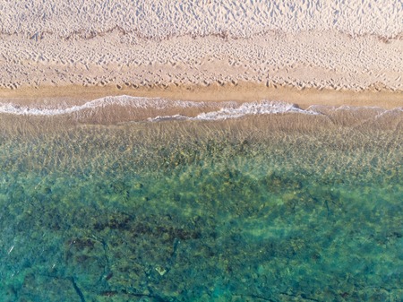 Drone aerial view from above of sandy beach, green and blue sea water.の写真素材