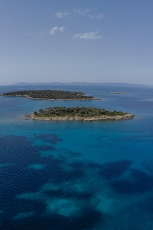 Two small islands surrounded with blue sea water with mountains in background. Drone aerial view.の写真素材