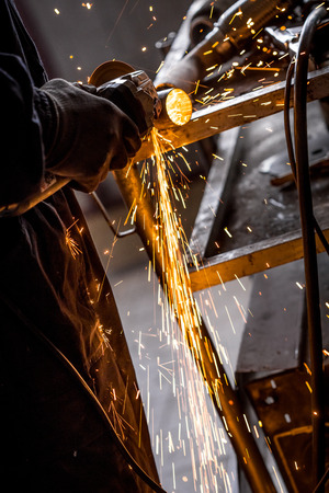 Close up of car mechanic hands welding grinding machine.Sparks of grinding machine while cutting car exhaust pipeの写真素材