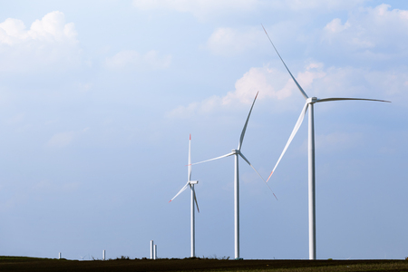 Windmill turbine farm with partly cloudy blue sky in background. Renewable energy wind turbinesの写真素材