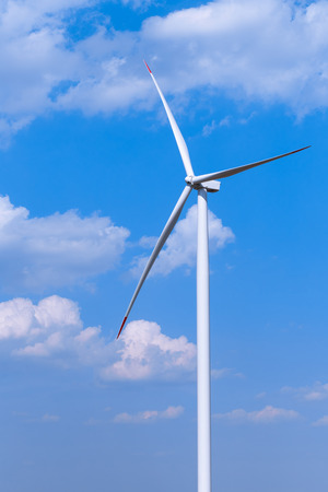 One single windmill turbine with partly cloudy blue sky in background. Renewable energy wind turbineの写真素材