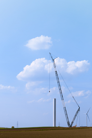 Blue crane tower constructing windmill with background of blue sky. Wind Turbine Construction.の写真素材