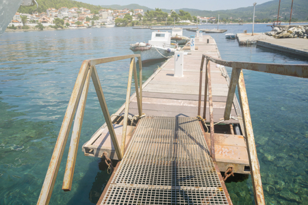 A metal bridge leading to the dock with boats.の写真素材