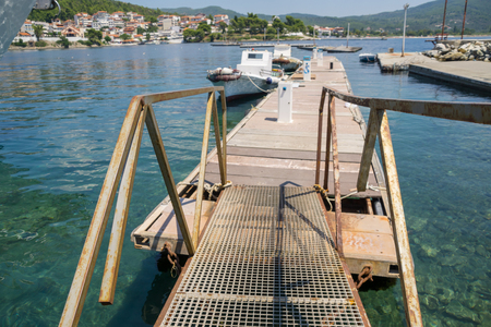 A metal bridge leading to the dock with boats.の写真素材