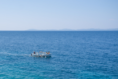 Small white motorized boat with one man sails in the open sea.の写真素材