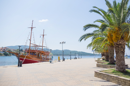 Big white brown wooden sailboat anchored next to the dock in town.の写真素材