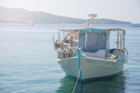 Small white overloaded fishing boat anchored next to the dock.の写真素材