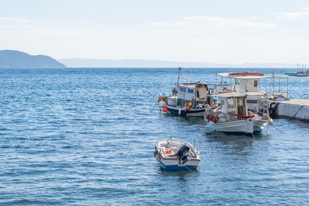 Small white overloaded fishing boats anchored next to the dock.の写真素材