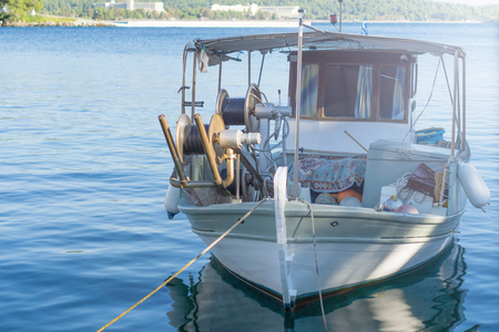 Small white overloaded fishing boat anchored next to the dock.の写真素材