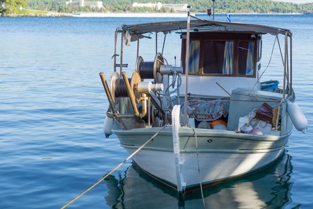 Small white overloaded fishing boat anchored next to the dock.の写真素材