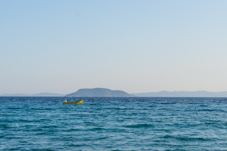 Small yellow motorized boat with one man sails in the open sea.の写真素材