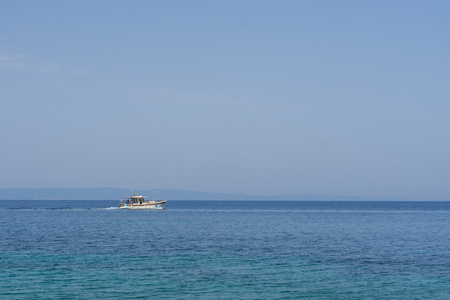 Small white motorized boat with one man sails in the open sea.の写真素材