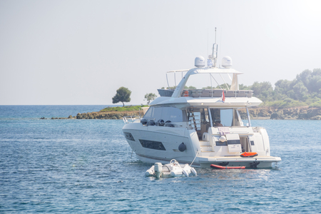 White yacht and small white boat anchored near shore.の写真素材
