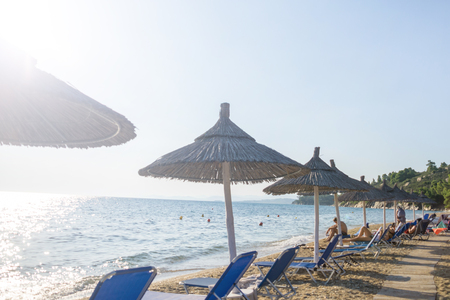 Umbrellas and deck chairs arranged in the row by the sea on the beachの写真素材
