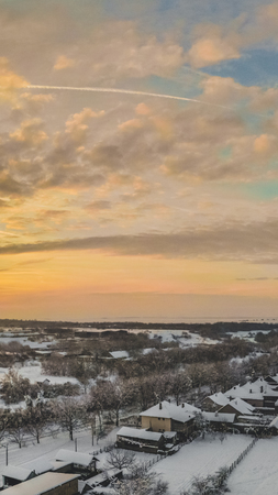 Aerial drone view of town roads and houses covered with snow on cloudy sunset.の写真素材