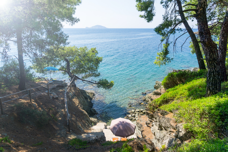 Blue sea water and small beach surrounded with rocks and treesの写真素材