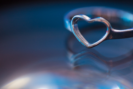 Silver heart shape ring with black blue background.の写真素材