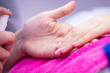 Women's hand on pink towel in nail salon.の写真素材