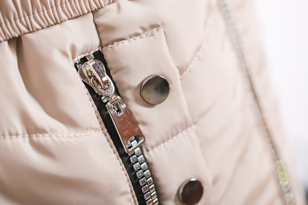 Close up of zipper on beige jacket pocket, winter fashion outfit. Jacket isolated on white background.の写真素材