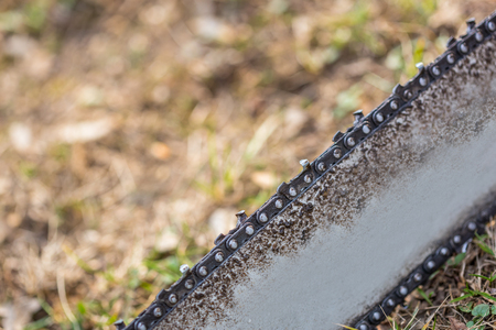 Close up of dirty chainsaw chain placed on ground on grass.の写真素材