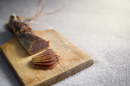 A dried ham on a wooden board cut into snacks.の写真素材
