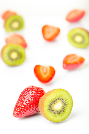 Red strawberries and green kiwi cut into half arranged on a white background.の写真素材