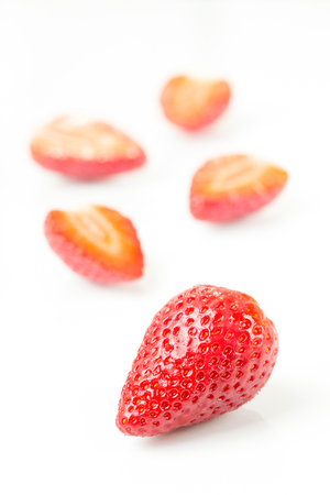 Red fresh cut and whole strawberries arranged on a white background.の写真素材