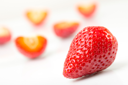 Red fresh cut and whole strawberries arranged on a white background.の写真素材