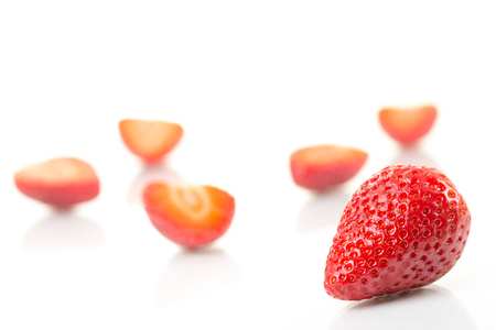 Red fresh cut and whole strawberries arranged on a white background.の写真素材