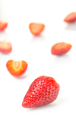 Red fresh cut and whole strawberries arranged on a white background.の写真素材