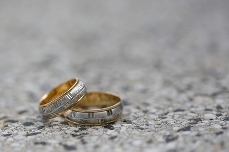 Golden wedding rings on a stone surface.