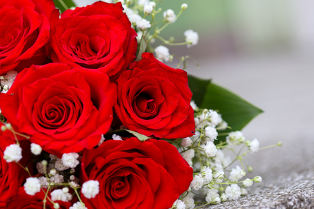 A bouquet of red roses with tiny white flowers and green leaves.の写真素材