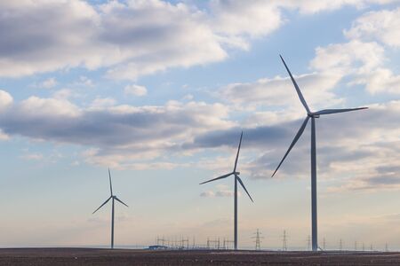 Three wind turbine on agricultural ground with cloudy sky in backgroundの写真素材
