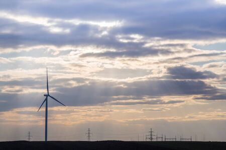 One wind turbine on agricultural ground with cloudy sky in backgroundの写真素材